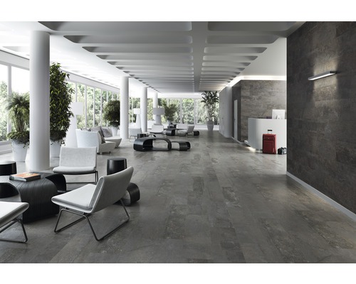 Großzügige Halle mit Bodenfliesen in Steinoptik, weißen Säulen und modernen Sitzmöbeln