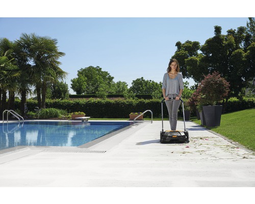 Frau benutzt eine Kehrmaschine im Außenbereich in der Nähe eines Pools.