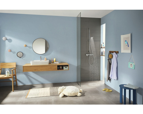 Badezimmer mit Dusche, Waschtisch, Spiegel und Accessoires in hellem Design