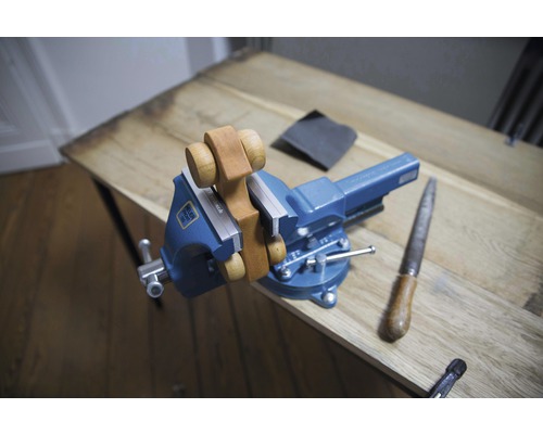 Eine Holzfigur ist in einem Schraubstock auf einem Tisch befestigt.