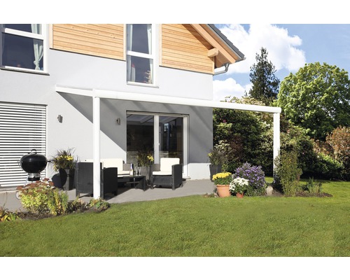 Terrasse mit Terrassenüberdachung, Gartenmöbeln und Grill auf Rasenfläche vor einem Wohnhaus