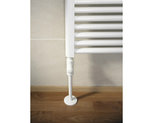 Weißer Röhrenheizkörper mit Thermostat vor Wand und Holzboden