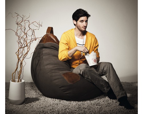 Mann sitzt auf einem braunen Sitzsack mit Lederdetails und isst aus einer Imbissbox