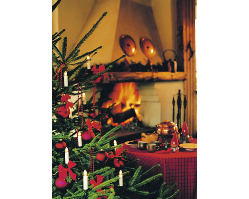 Weihnachtsbaum mit Dekoration, Beleuchtung und festlich gedecktem Tisch vor Kamin