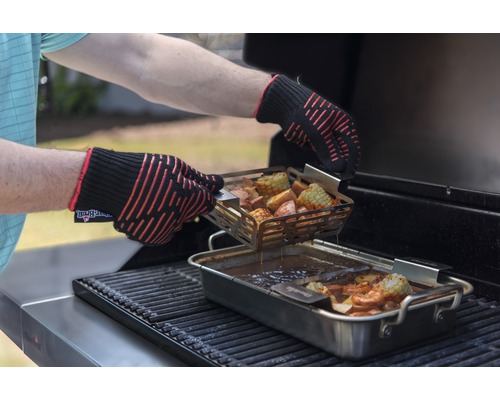 Person mit Ofenhandschuhen bereitet Speisen auf dem Grill zu.