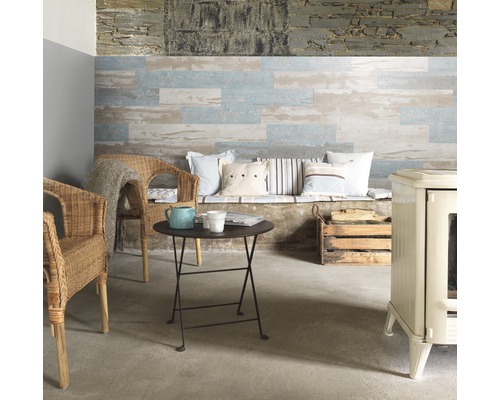 Wohnzimmer mit Holzwandpaneelen, Rattansesseln, kleinem Tisch und Ofen