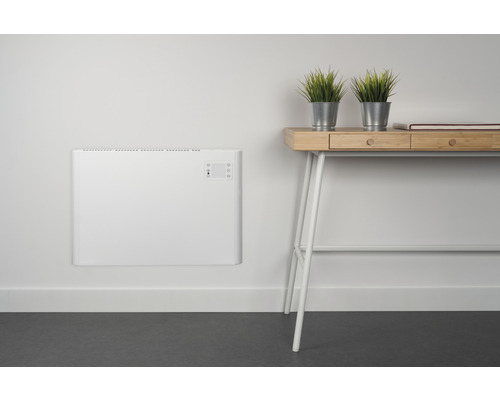 Wandmontierter Heizkörper neben einem Schreibtisch mit dekorativen Pflanzen.