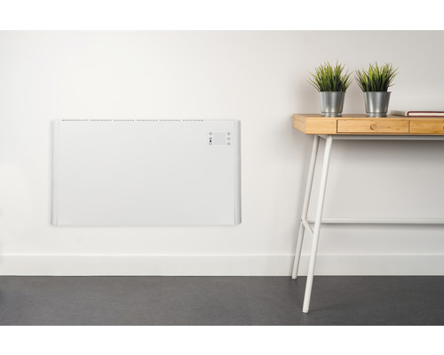 Wandmontierter, weißer Heizkörper neben einem Schreibtisch mit Pflanzen
