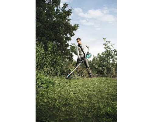 Ein Mann benutzt einen Rasentrimmer in einem Garten zum Rasenschneiden.