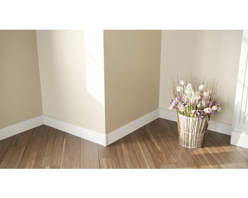 Raumecke mit weißen Fußleisten, Holzboden und einem Blumenstrauß in einem dekorativen Gefäß.