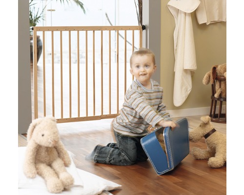 Ein Kind spielt vor einem Holzkindergitter