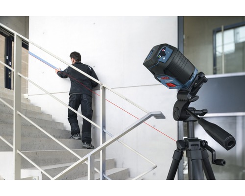 Baustelle mit Linienlaser auf Stativ und Handwerker auf Treppe