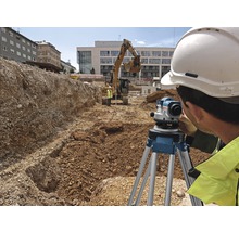 Bauarbeiter bei der Arbeit mit einem Nivelliergerät auf einer Baustelle