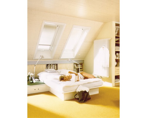 Helles Dachzimmer mit Dachfenstern, Bett und Frau