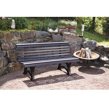 Gartenbank aus Holz und Metall vor einer Steinmauer mit Dekoration