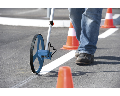 Person misst mit Messrad auf Asphalt