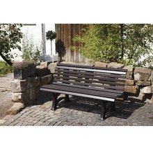 Garten Szene mit Steinmauer und einer Gartenbank aus Metall.