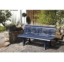 Blaue Gartenbank aus Metall auf gepflastertem Untergrund vor Steinmauer