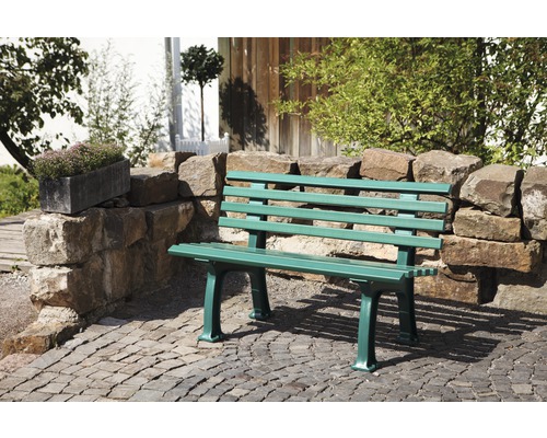 Grüne Gartenbank aus Holz und Steinmauer im Außenbereich