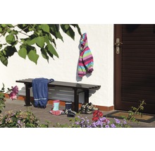 Szene mit Bank, Kinderkleidung und Schuhen vor einem Haus