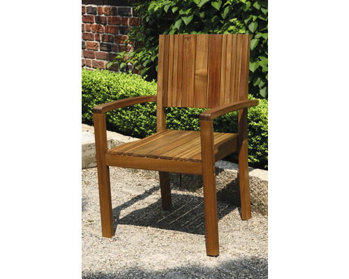 Gartenstuhl aus Holz mit Armlehnen vor Grünpflanzen und einer Backsteinmauer