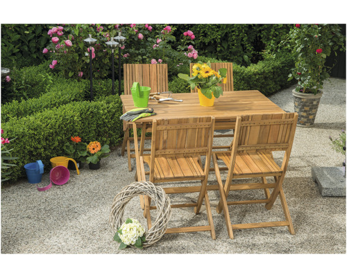 Gartenszene mit Holztisch und Stühlen, umgeben von Pflanzen und Gartendekorationen