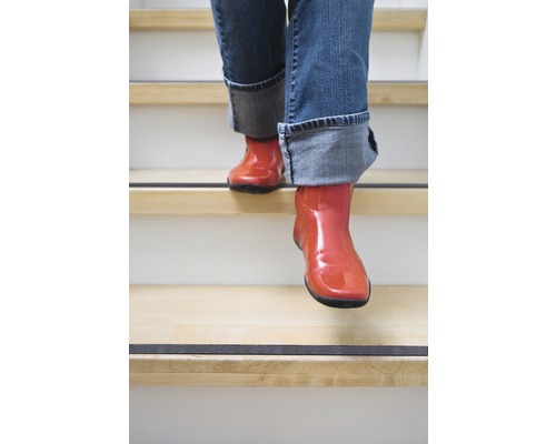 Person in Stiefeln geht Treppe mit Antirutschstreifen hinunter