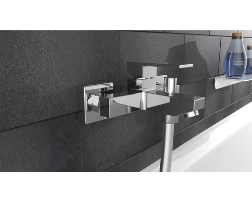 Wannenarmatur aus Chrom an einer dunklen Wand mit Badaccessoires