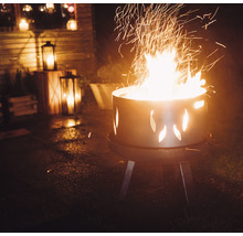 Brennendes Feuer in einer Feuerstelle mit Ausschnitten im Garten