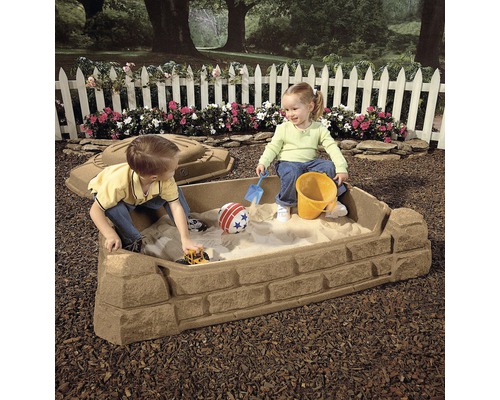 Sandkasten mit zwei Kindern, Sandspielzeug und Deckel im Garten.