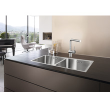 Edelstahlspüle mit zwei Becken und Armatur auf einer Arbeitsplatte.