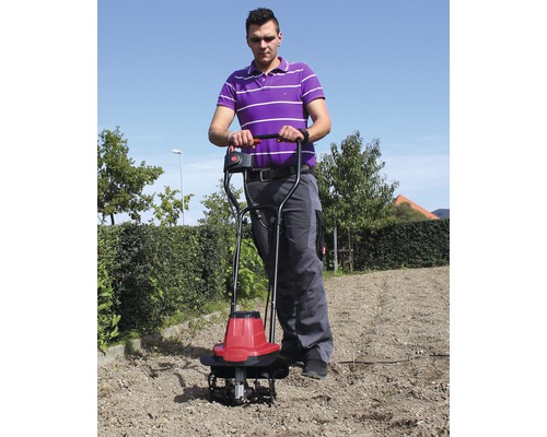Ein Mann benutzt eine Motorhacke zur Bodenbearbeitung im Garten.