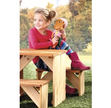 Mädchen sitzt mit Puppe an einem Kindersitzgarnitur im Garten