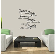 Wohnzimmer mit Sofa, Tisch und Wandtattoo mit Spruch.