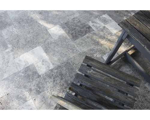 Bodenbelag aus Natursteinfliesen und Holzstuhl