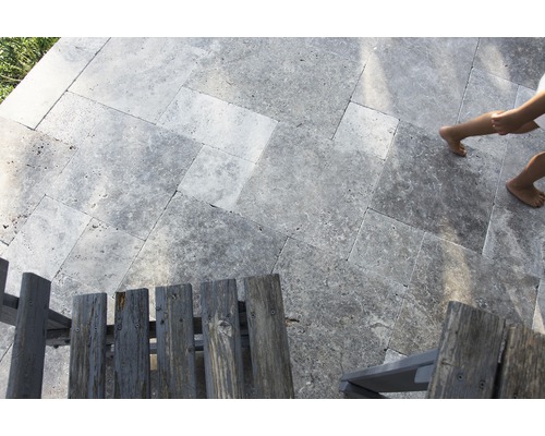 Verlegung von Travertinfliesen im Außenbereich mit Holzstühlen