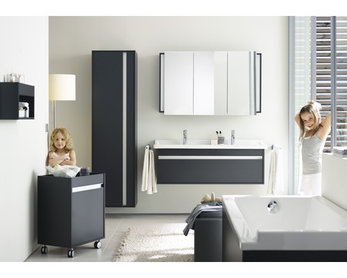 Helles Badezimmer mit Waschtisch, Spiegelschrank, Hochschrank, Rollcontainer, Badewanne und zwei Mädchen