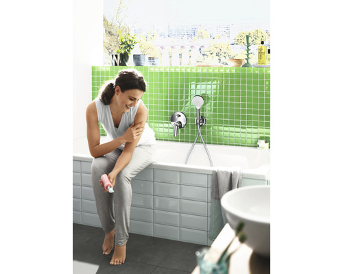 Helles Badezimmer mit Badewanne, Armatur und Frau, die sich eincremt.