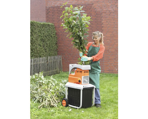 Frau bedient einen Gartenhäcksler von Atika zum Zerkleinern von Ästen und Grünabfällen