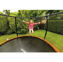 Mädchen springt auf Gartentrampolin mit Sicherheitsnetz