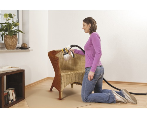 Frau lackiert Korbsessel mit Farbsprühsystem