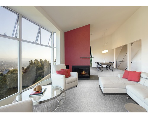 Wohnzimmer mit großem Fenster, Sessel, Sofa, Teppich und Kamin.