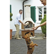 Szene mit einem Mann, der Holz in einen Gartengrill legt, während eine Frau einem Hund ein Leckerli gibt.