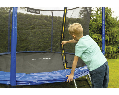 Junge an einem Trampolin mit Sicherheitsnetz im Garten
