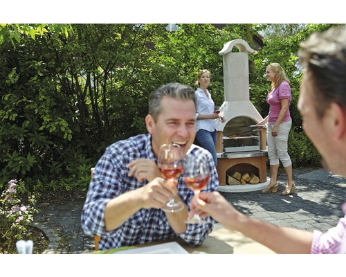 Szene mit einem Steingrill im Garten, wo eine Gruppe von Menschen grillt und mit Weingläsern anstößt.