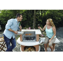 Mann und Frau grillen im Garten mit einem Steingrill und Holzkohle.