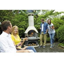 Grillkamin mit brennendem Holz und Menschen im Garten.