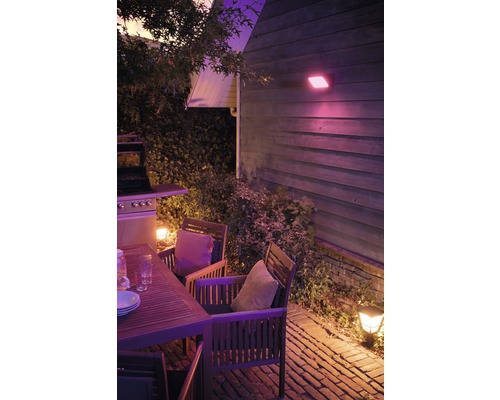 Beleuchtete Terrasse mit Holztisch, Stühlen und Grill