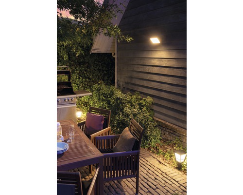 Außenbereich mit Gartentisch, Stühlen, Grill und Außenleuchten.