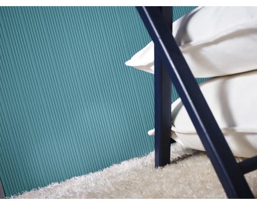 Detailansicht einer Wand mit geriffelter Tapete, einem Stapel Kissen und einem Teppich